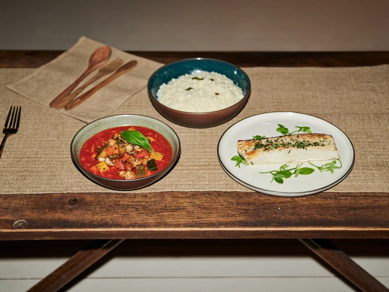 Minestrone, risotto e pesce al forno in ciotole di ceramica rustica