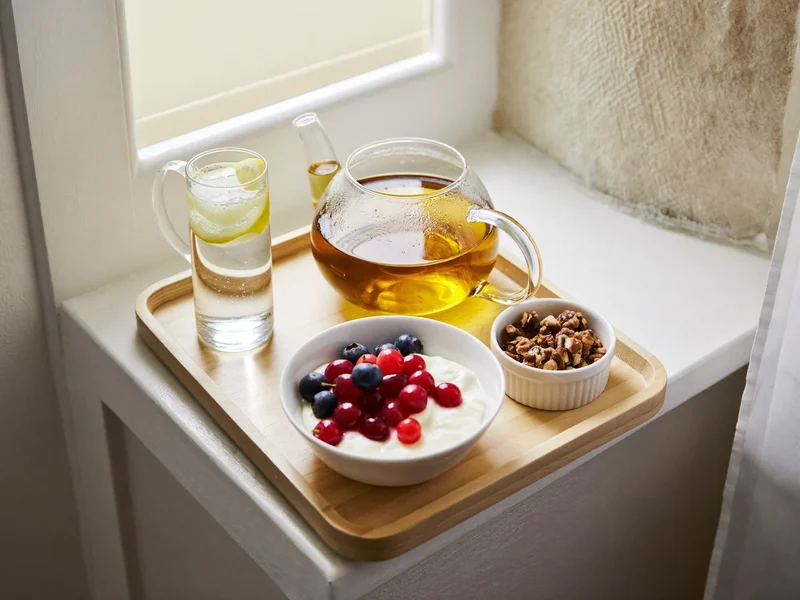 Tisana, acqua con limone, yogurt con frutti di bosco e noci su un vassoio